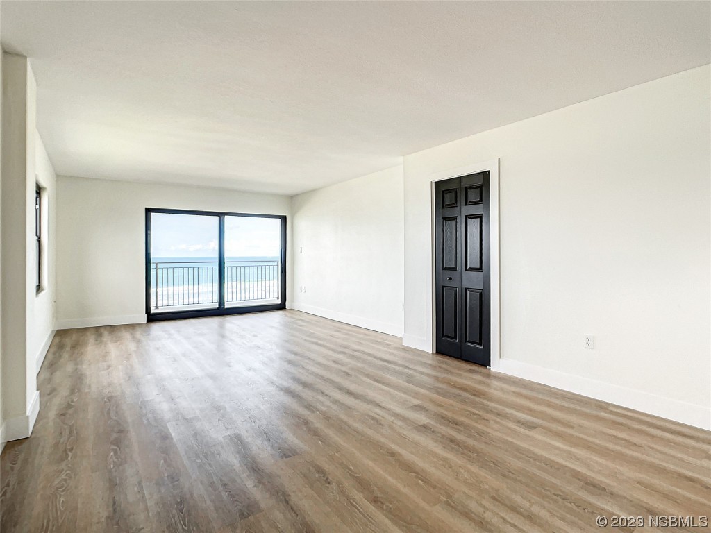4435 South Atlantic Avenue, Unit 311 Ponce Inlet, FL 32127 - Photo 16 of 44 an empty room with wooden floor and windows