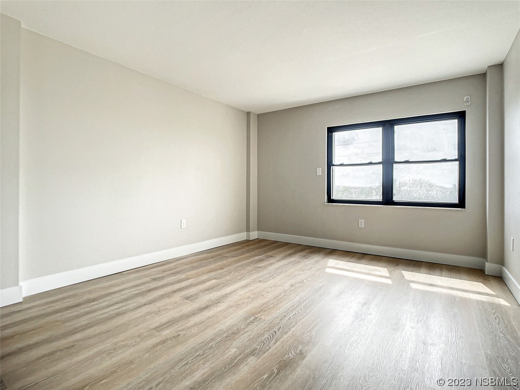 4435 South Atlantic Avenue, Unit 311 Ponce Inlet, FL 32127 - Photo 19 of 44 an empty room with wooden floor and windows
