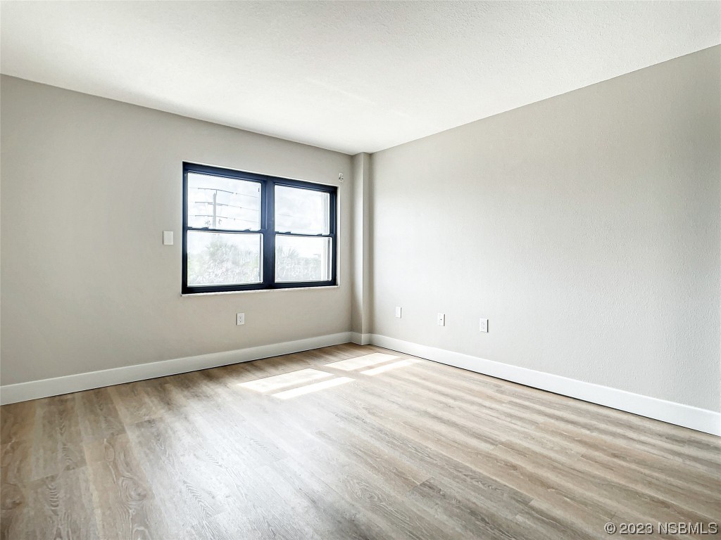 4435 South Atlantic Avenue, Unit 311 Ponce Inlet, FL 32127 - Photo 20 of 44 an empty room with wooden floor and windows