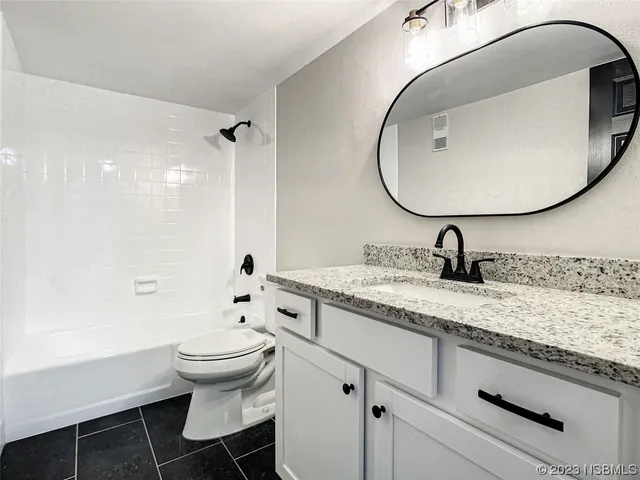 a bathroom with a granite countertop toilet sink and mirror