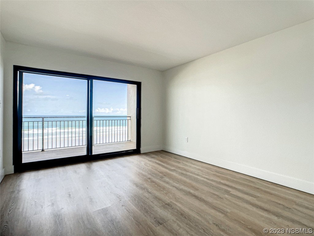 4435 South Atlantic Avenue, Unit 311 Ponce Inlet, FL 32127 - Photo 27 of 44 an empty room with wooden floor and windows