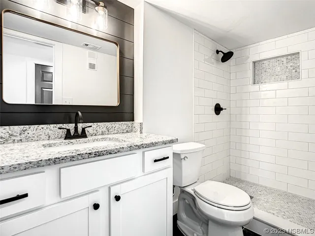 a bathroom with a granite countertop toilet sink and mirror