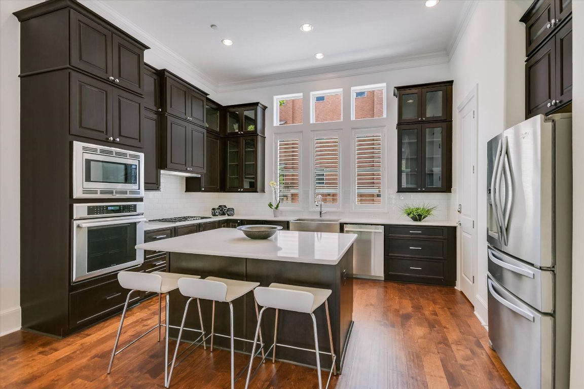 1023 Juniper Street Austin, TX 78702 - Photo 3 of 31 a kitchen with stainless steel appliances kitchen island granite countertop a refrigerator a stove and a sink with wooden floor