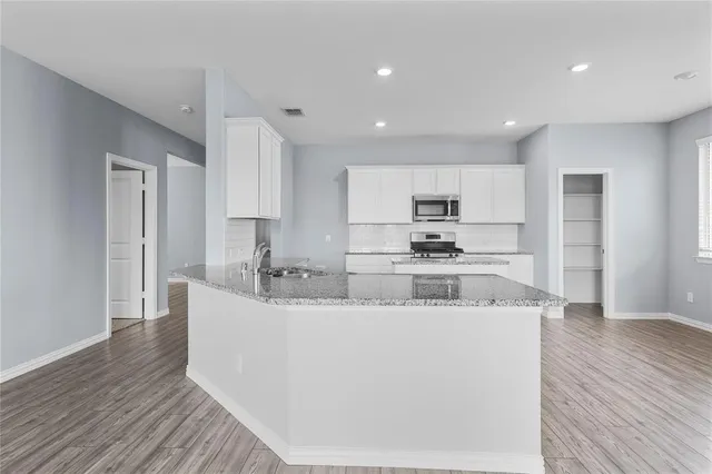 a kitchen with stainless steel appliances granite countertop a sink a refrigerator and a stove top oven