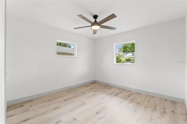 an empty room with wooden floor and ceiling fan