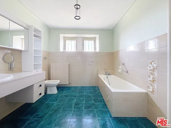 a spacious bathroom with a double vanity sink a large mirror and a toilet