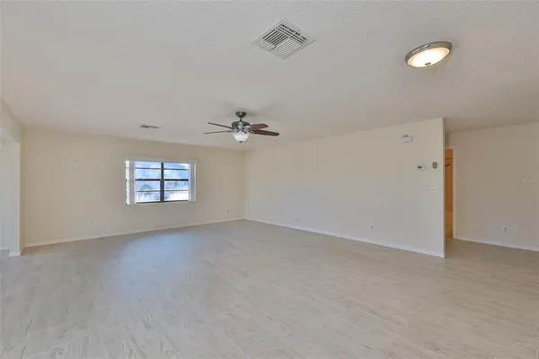 an empty room with windows and fan