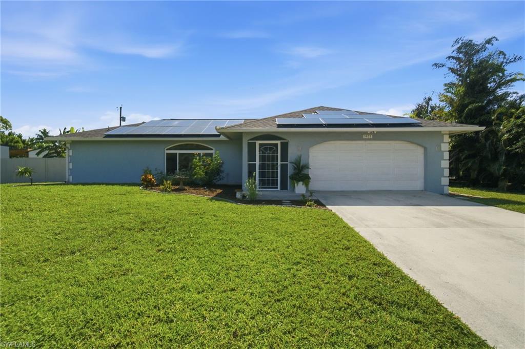 3022 47th Street Southwest Naples, FL 34116 - Photo 1 of 46 Single-story residence featuring a two-car garage, concrete driveway, and a shingled roof with visible solar panels