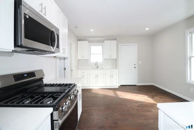 a kitchen with granite countertop a stove and a flat screen tv