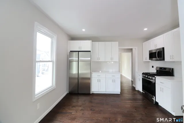 a kitchen with stainless steel appliances a refrigerator a stove a sink and a window