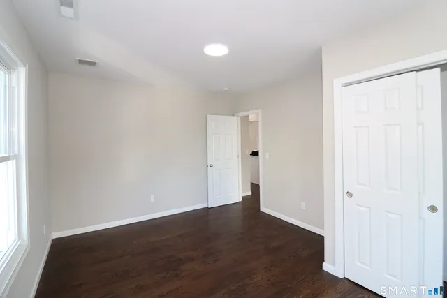 an empty room with wooden floor and windows with curtains