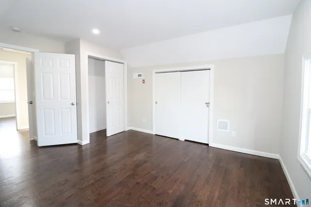 an empty room with wooden floor & closet area