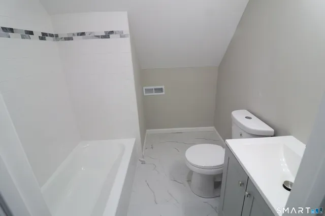 a white toilet sitting next to a bath tub