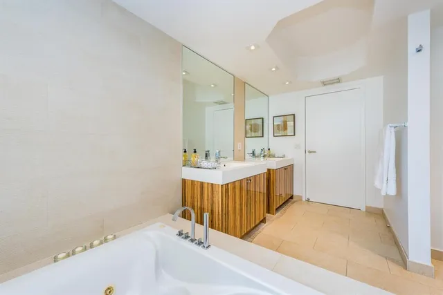 a bathroom with a tub a sink and a mirror