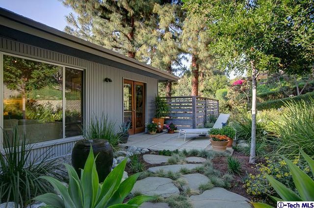 a backyard of a house with table and chairs under an umbrella