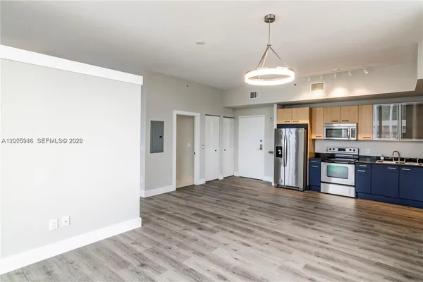 a view of a kitchen center island wooden floor and stainless steel appliances