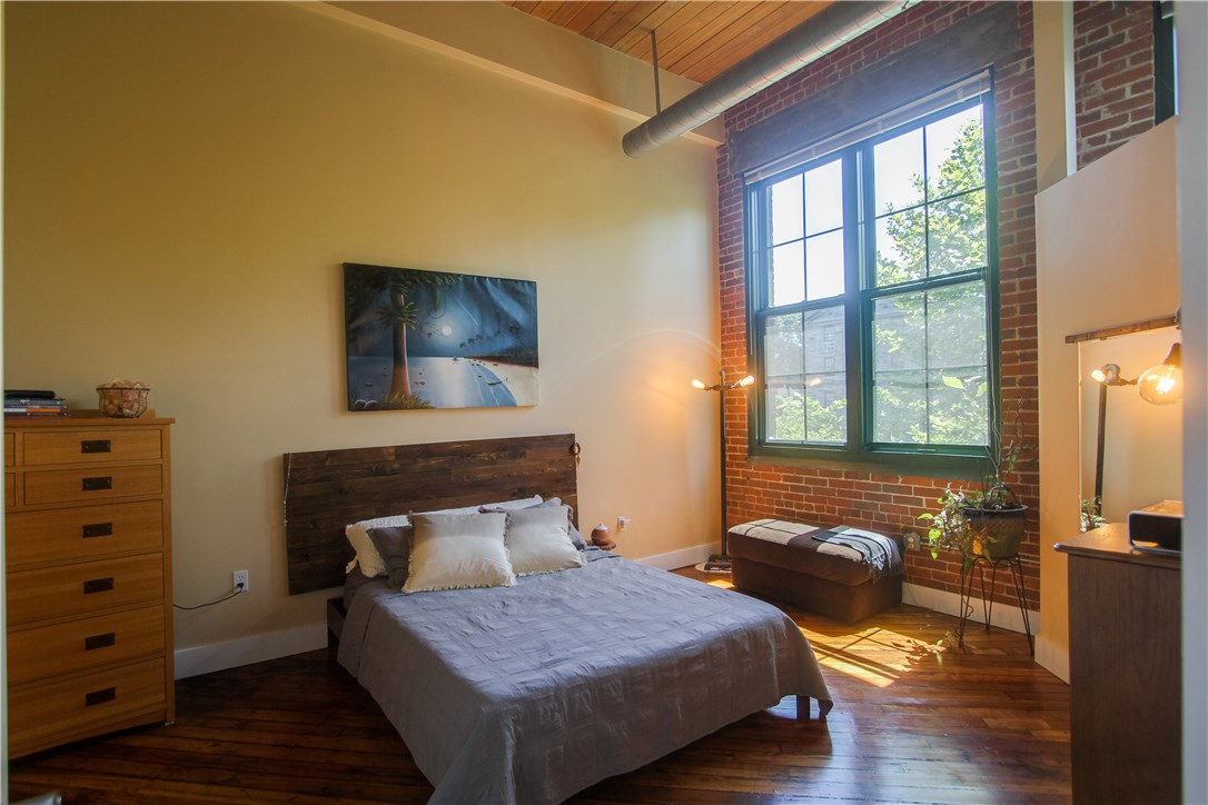 99 Allen Street, Unit 204 Woonsocket, RI 02895 - Photo 8 of 17 The bedroom typifies the industrial "chic" look with original hardwoods and brick and exposed ductwork. The Bernon Mill complex right across the river completes the picture.