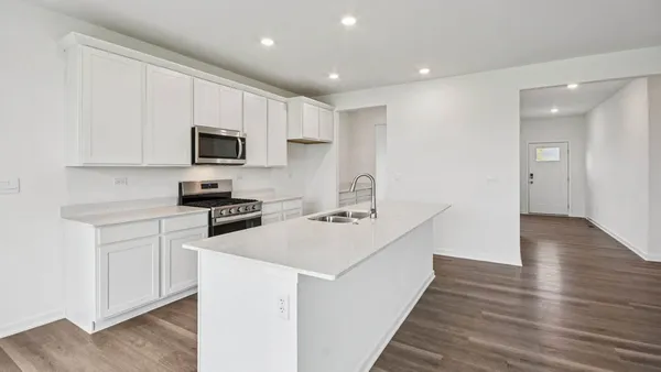 a kitchen with stainless steel appliances a stove top oven a sink a refrigerator white cabinets and wooden floor