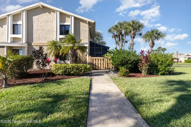a front view of a house with a yard and potted plants