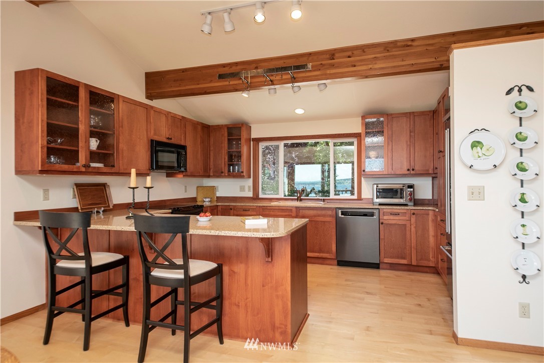6188 Double Bluff Road Freeland, WA 98249 - Photo 25 of 40 a kitchen with stainless steel appliances granite countertop a stove top oven a sink dishwasher and a refrigerator with wooden cabinets
