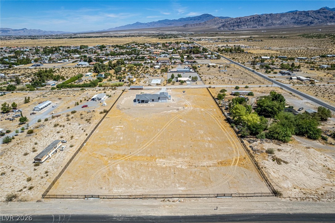 5910 East Kellogg Road Pahrump, NV 89061 - Photo 51 of 58 A desert oasis with sprawling land and a new construction home, set against a mountain backdrop.