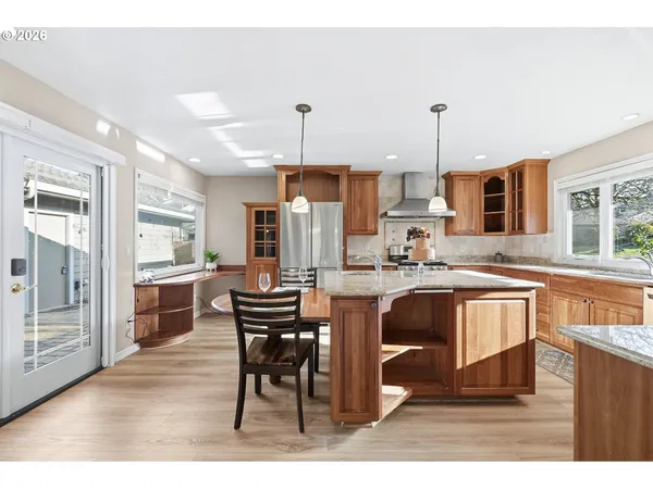 a kitchen with stainless steel appliances kitchen island a table chairs in it and wooden floors