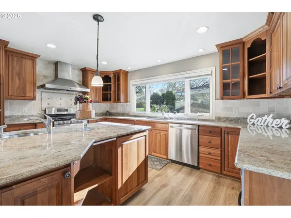 a kitchen with stainless steel appliances granite countertop a sink a stove and a wooden floors