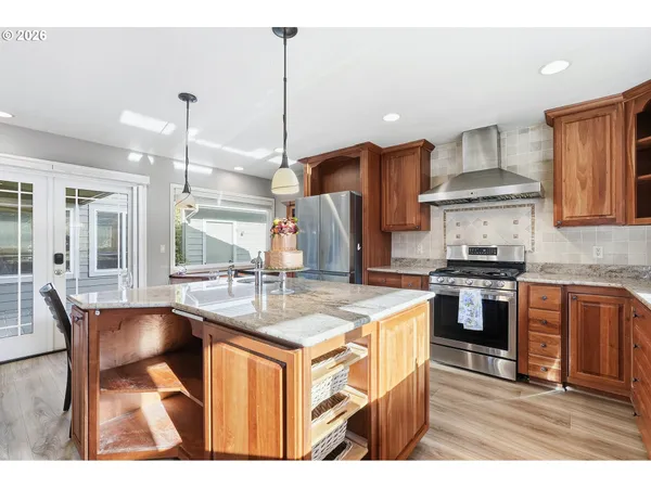 a kitchen with stainless steel appliances granite countertop a kitchen island a stove a table and chairs