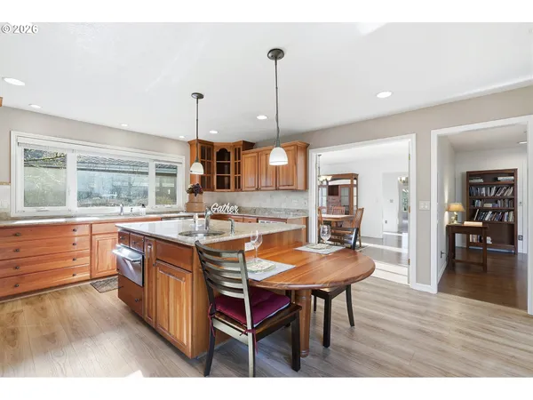 a kitchen with stainless steel appliances granite countertop a dining table chairs refrigerator and microwave