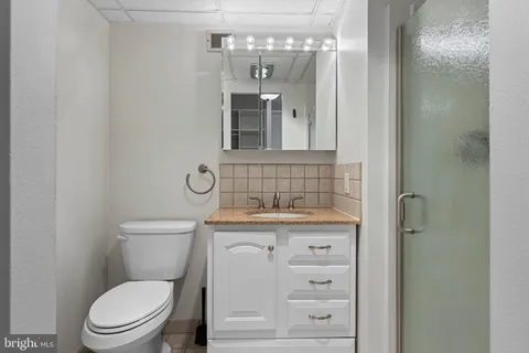 a bathroom with a granite countertop toilet a sink and a mirror