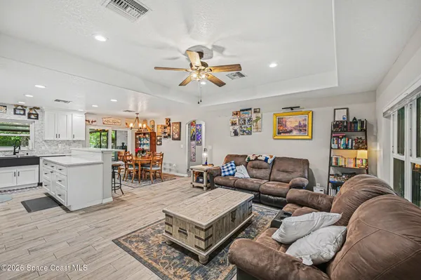 a living room with furniture kitchen view and a chandelier