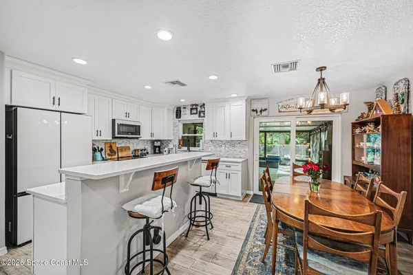 a kitchen with stainless steel appliances kitchen island granite countertop a dining table chairs refrigerator and sink