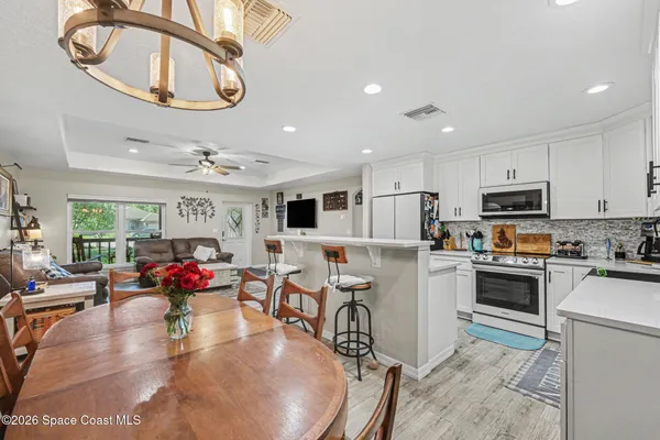 a kitchen with stainless steel appliances granite countertop a stove top oven a sink dishwasher and a dining table with kitchen view