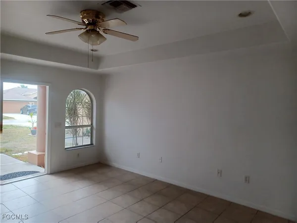 an empty room with windows and ceiling fan