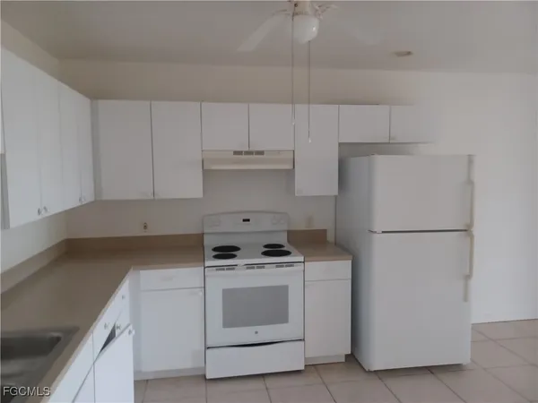 a kitchen with a stove a refrigerator and white cabinets