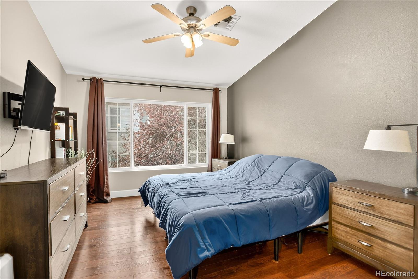 8415 Pebble Creek Way, Unit 203 Highlands Ranch, CO 80126 - Photo 14 of 36 a bedroom with a bed and a flat tv screen on dresser
