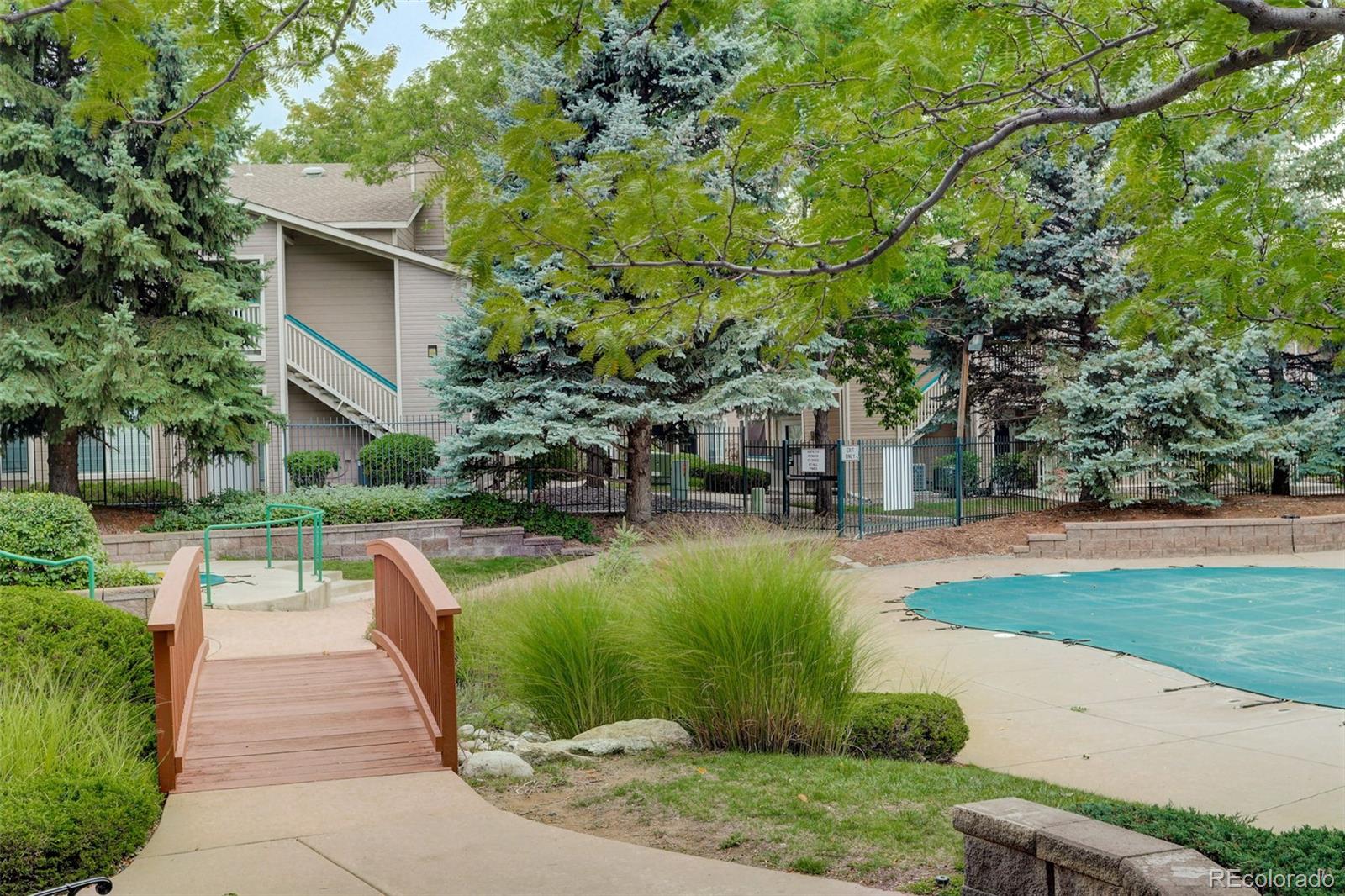 8415 Pebble Creek Way, Unit 203 Highlands Ranch, CO 80126 - Photo 33 of 36 a view of a patio with table and chairs potted plants and large tree