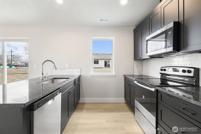 a kitchen with granite countertop a sink stainless steel appliances and cabinets