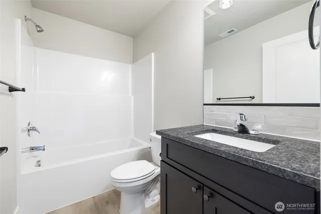 a bathroom with a granite countertop sink toilet and shower
