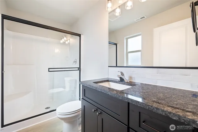 a bathroom with a granite countertop sink mirror vanity and toilet