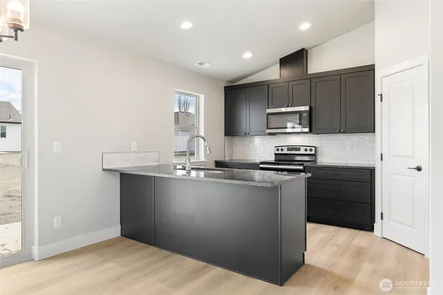 a kitchen with stainless steel appliances granite countertop a refrigerator and a stove top oven