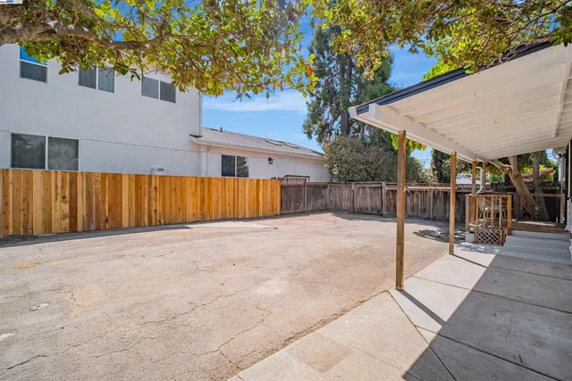 a view of backyard with wooden fence and a bench