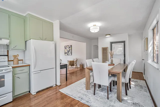 a view of a dining room with furniture a refrigerator and wooden floor