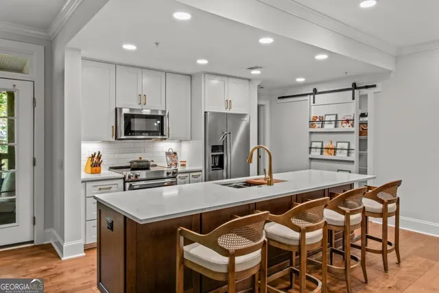 a kitchen with stainless steel appliances a stove a sink a microwave a refrigerator and cabinets