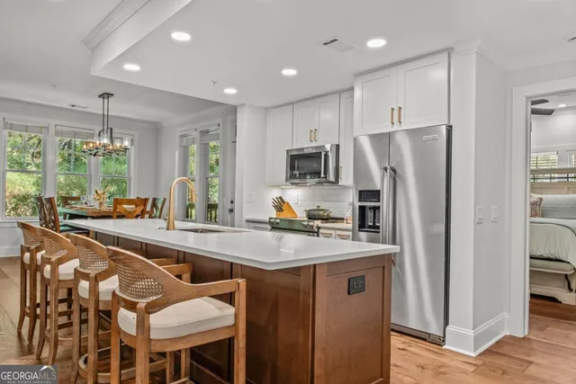 a kitchen with stainless steel appliances granite countertop a refrigerator a sink dishwasher a stove and a refrigerator with wooden floor