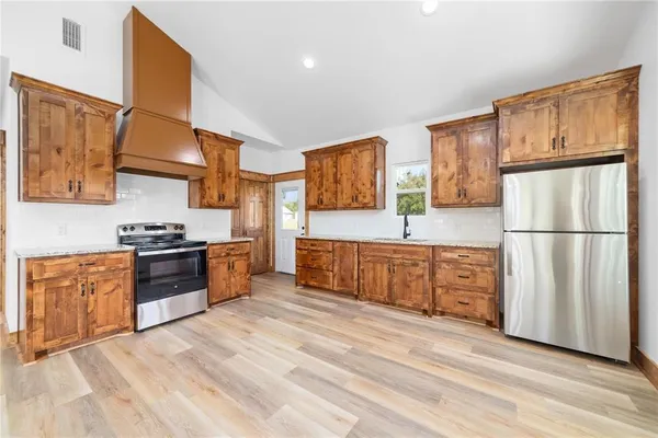 a large kitchen with stainless steel appliances granite countertop a stove a sink dishwasher a refrigerator and cabinets with wooden floor