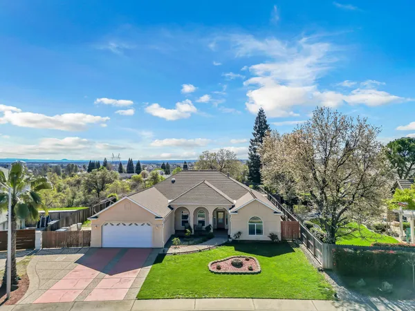 a view of a house with a big yard plants and large tree