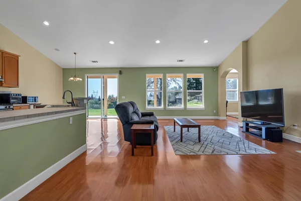 a living room with furniture wooden floor and a kitchen view