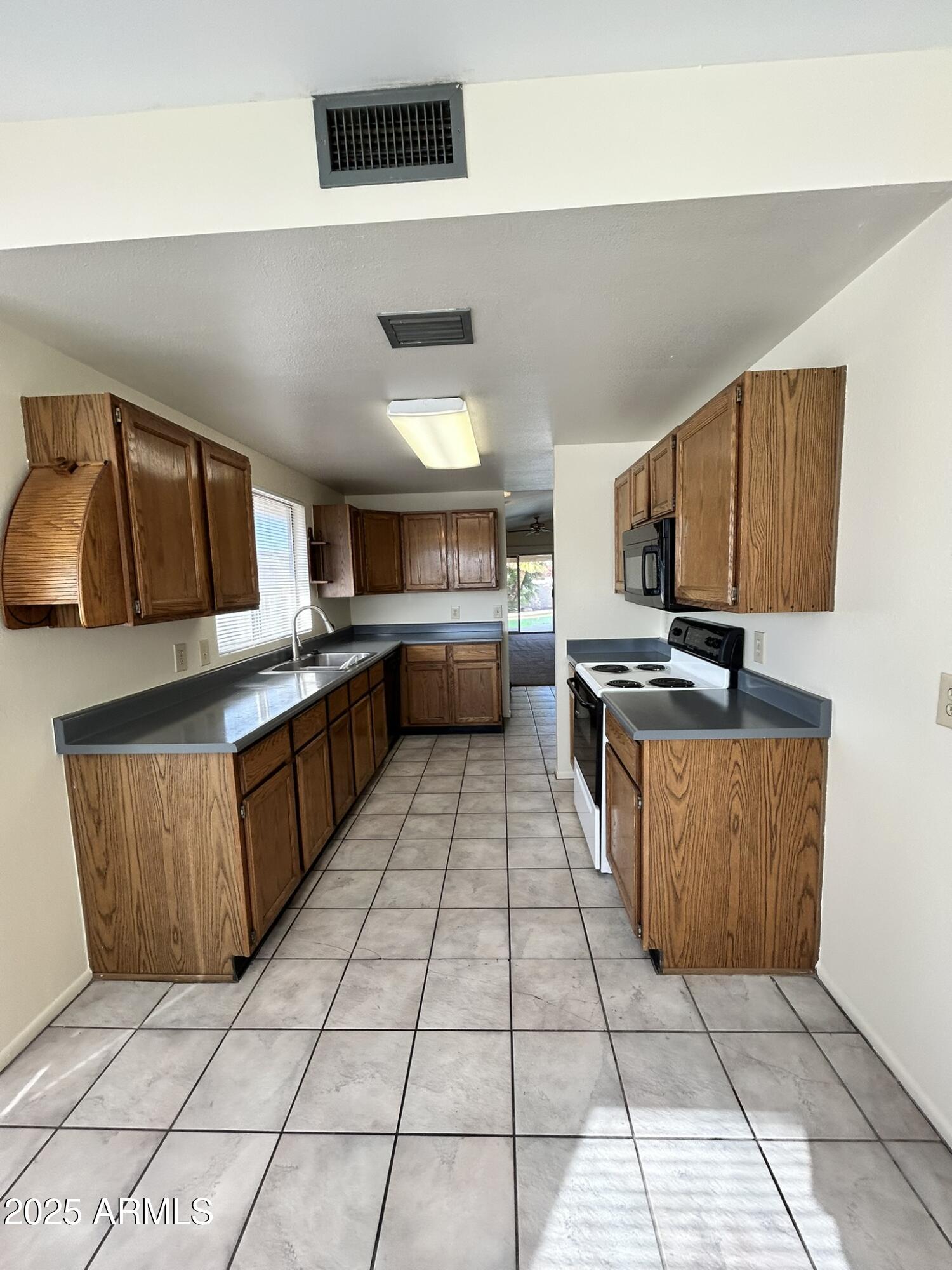 2120 North Yucca Court Chandler, AZ 85224 - Photo 12 of 32 a large kitchen with a stove a sink dishwasher and a stove top oven with wooden cabinets