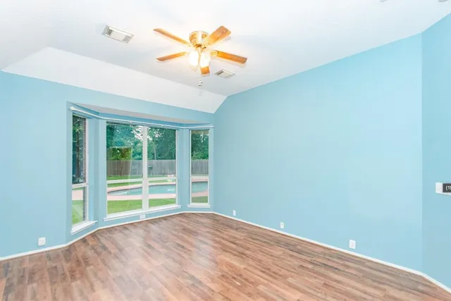 an empty room with a window and a ceiling fan